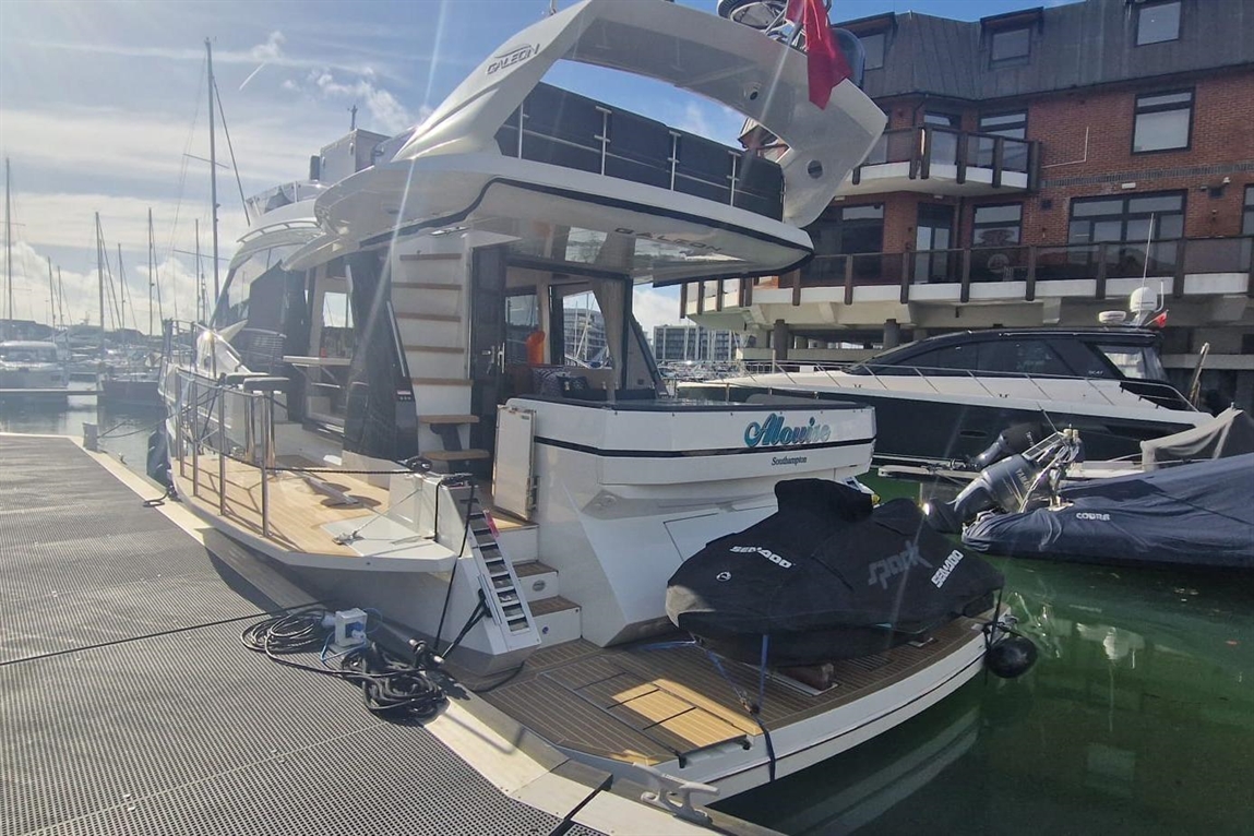 A luxury boat named "Alovice" docked in a marina with yachts, wooden deck, and a scenic waterfront view in Southampton.